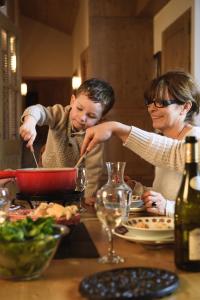 a woman and a child sitting at a table eating food at CGH Résidences & Spas Les Granges Du Soleil in La Plagne