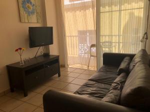 uma sala de estar com um sofá e uma televisão de ecrã plano em Apartamentos El Faro em Puerto Naos