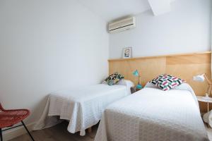 um quarto com 2 camas e uma cadeira vermelha em Apartamento Alameda em Sevilha
