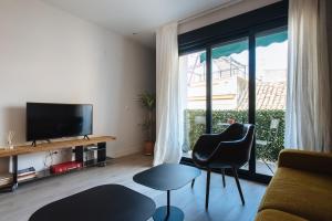uma sala de estar com uma televisão de ecrã plano e cadeiras em Apartamento Alameda em Sevilha