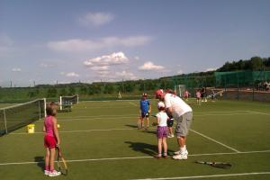 a man and two children standing on a tennis court at Sportpenzion Pohoda in Pilsen