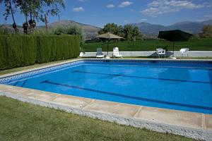 a large blue swimming pool with chairs and umbrellas at La "Casita" de la Sierra in Guadarrama