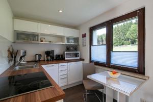 a kitchen with white cabinets and a table and a window at Ferienhaus Nadine 2023 komplett saniert in Bad Brambach