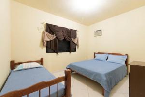 a bedroom with two beds and a window with curtains at Pousada Dona Ema in Balneário Camboriú
