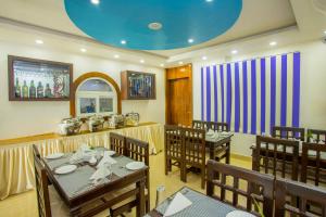 Hotel Lakeside Pvt. Ltd. في بوخارا: غرفة طعام بها طاولات وكراسي وسقف أزرق