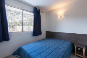 a bedroom with a blue bed and a window at Relais de la Guisane in Briançon