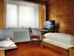 a bedroom with a bed and a desk with a computer at Landhotel Kaserer in Bramberg am Wildkogel
