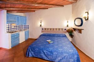 a room with a bed in a kitchen with blue cabinets at Camping Baia Saraceno in Palau