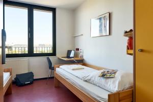 a room with a bed and a desk with a computer at Jugendherberge Frankfurt - Haus der Jugend in Frankfurt/Main