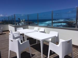 コティージョにあるPiso Oliasturの白いテーブルと椅子、海を望むバルコニー
