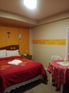 1 dormitorio con 1 cama con manta roja y mesa en Hotel "VIRGEN DEL SOCAVON", en Oruro