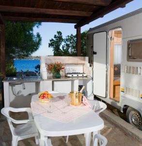 an rv with a white table with a bowl of fruit at Camping Baia Saraceno in Palau