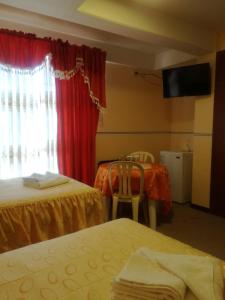 una camera d'albergo con due letti e una televisione di Hotel "VIRGEN DEL SOCAVON" a Oruro