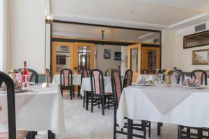 uma sala de jantar com mesas e cadeiras brancas em Hotel Lido em Gargnano