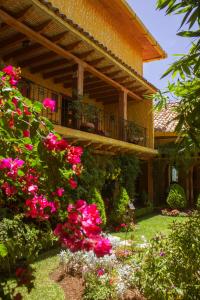 uma casa com varanda e flores cor-de-rosa em Hotel Posada Primavera em San Cristóbal de Las Casas
