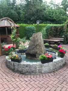 a garden with a fountain with flowers and a rock at Hotel Daun in Castrop-Rauxel