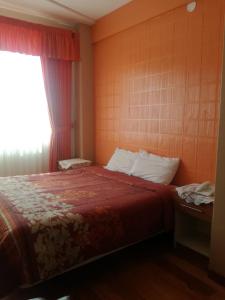 1 dormitorio con 1 cama con colcha roja y ventana en The Oruro Inn en Oruro