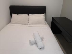 Una cama blanca con dos rollos de toallas. en VORTEX SUITES KLCC by PNUT With NETFLIX, en Kuala Lumpur