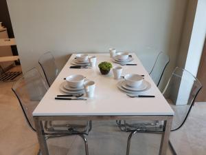 una mesa blanca con sillas, tazas y platos. en VORTEX SUITES KLCC by PNUT With NETFLIX, en Kuala Lumpur