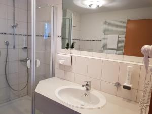 een witte badkamer met een wastafel en een douche bij Hotel Habana in Aalen