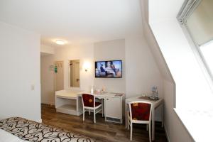 an attic room with a desk and chairs and a window at Hotel Märkischer Hof in Luckenwalde