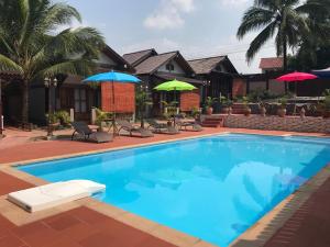 una piscina frente a una casa con sombrillas en Thongbay Guesthouse, en Luang Prabang