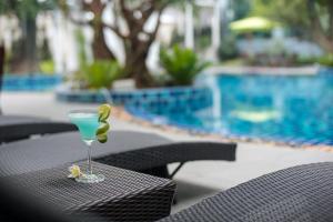 een martini glas op een tafel naast een zwembad bij Bay Beach Resort Jomtien in Jomtien Beach +75 foto's