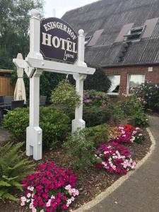 a sign for a hotel with flowers in a garden at Hotel Esinger Hof garni in Tornesch