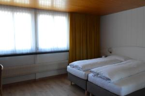 two beds in a room with two windows at Hotel Garni Rösslipost in Unteriberg