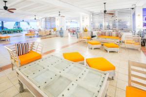 モンテゴ・ベイにあるGrand Decameron Montego Beach, A Trademark All-Inclusive Resortのオレンジと白の椅子とテーブルが備わるレストラン
