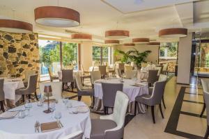 a restaurant with white tables and chairs and windows at Ngonia Bay Boutique Hotel in Milazzo