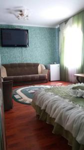 ein Wohnzimmer mit einem Sofa und einem Flachbild-TV in der Unterkunft Hotel Tropicana in Svitlovodsʼk