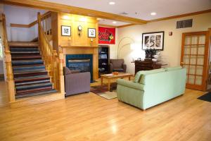 a living room with a staircase and a couch and a fireplace at Country Inn & Suites by Radisson, Bloomington-Normal West, IL in Bloomington