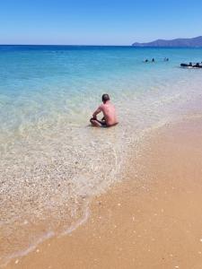 un hombre sentado en el agua en la playa en Résidence EL AMAL, en Martil