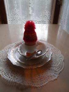 une tasse avec un chapeau rouge sur une plaque sur une table dans l'établissement Chambres d'hôtes Les Nefliers, à Amboise