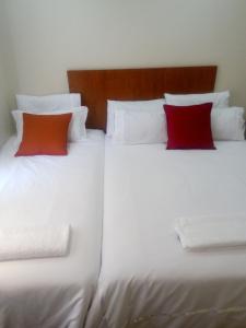 a large white bed with two red pillows on it at Eros Guest Inn in Francistown