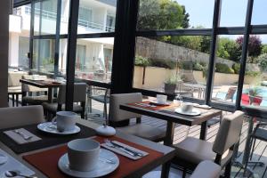 a restaurant with tables and chairs and a large window at Le Churchill Hôtel & Spa in Carnac