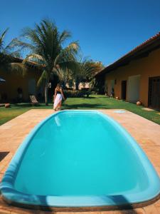 une femme qui passe devant une piscine bleue dans l'établissement Pouso do Kite Pousada Flecheiras, à Flecheiras