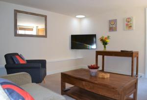 a living room with a couch and a tv on the wall at The Old Bottle Store - 2 Double Bedrooms, 2 Bathrooms, St Ives, Cambridgeshire in St. Ives