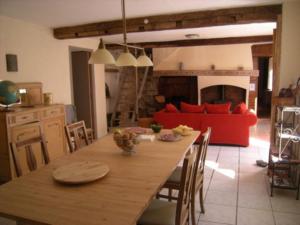 una cucina e una sala da pranzo con tavolo e divano rosso di La Maison du Voyageur a Les Ilhes