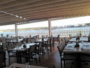 a restaurant with tables and chairs with a view of the ocean at Hotel Roca Bella in Es Pujols