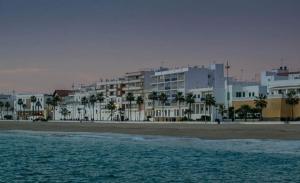 ロタにあるAPARTAMENTO PUERTA AL MARの白い建物と海の景色を望むビーチの景色