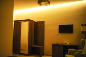 um quarto de hotel com uma televisão e uma cadeira em Vine Rooms em Oradea