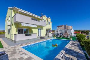 a person swimming in a swimming pool in front of a house at Holiday home Villa Anny in Brodarica