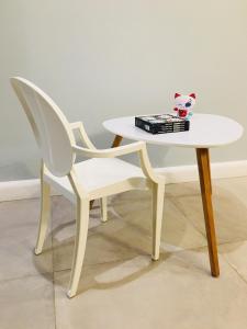 een witte tafel en een witte stoel met een boek bij Piper Cytadela Apartament in Poznań