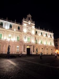 a large white building with a clock tower at night at Suite Il Letto Sotto Il Tetto in Catania