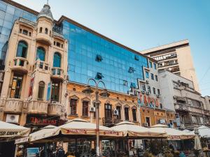 a large glass building with umbrellas in front of it at Central Plaza Apartments in Niš