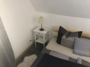 ein kleines Schlafzimmer mit einem Bett und einem Tisch mit einer Lampe in der Unterkunft Schöne‘s Eck in Großröhrsdorf