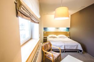 オストルフ・ビエルコポルスキにあるHotel Platanのベッドルーム1室(ベッド1台、椅子、窓付)