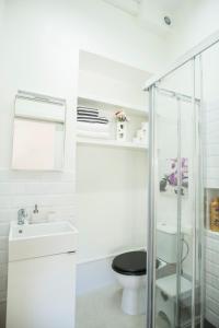 a white bathroom with a toilet and a glass shower at Suite Plaza de la Laguna by Dulce in Ayamonte